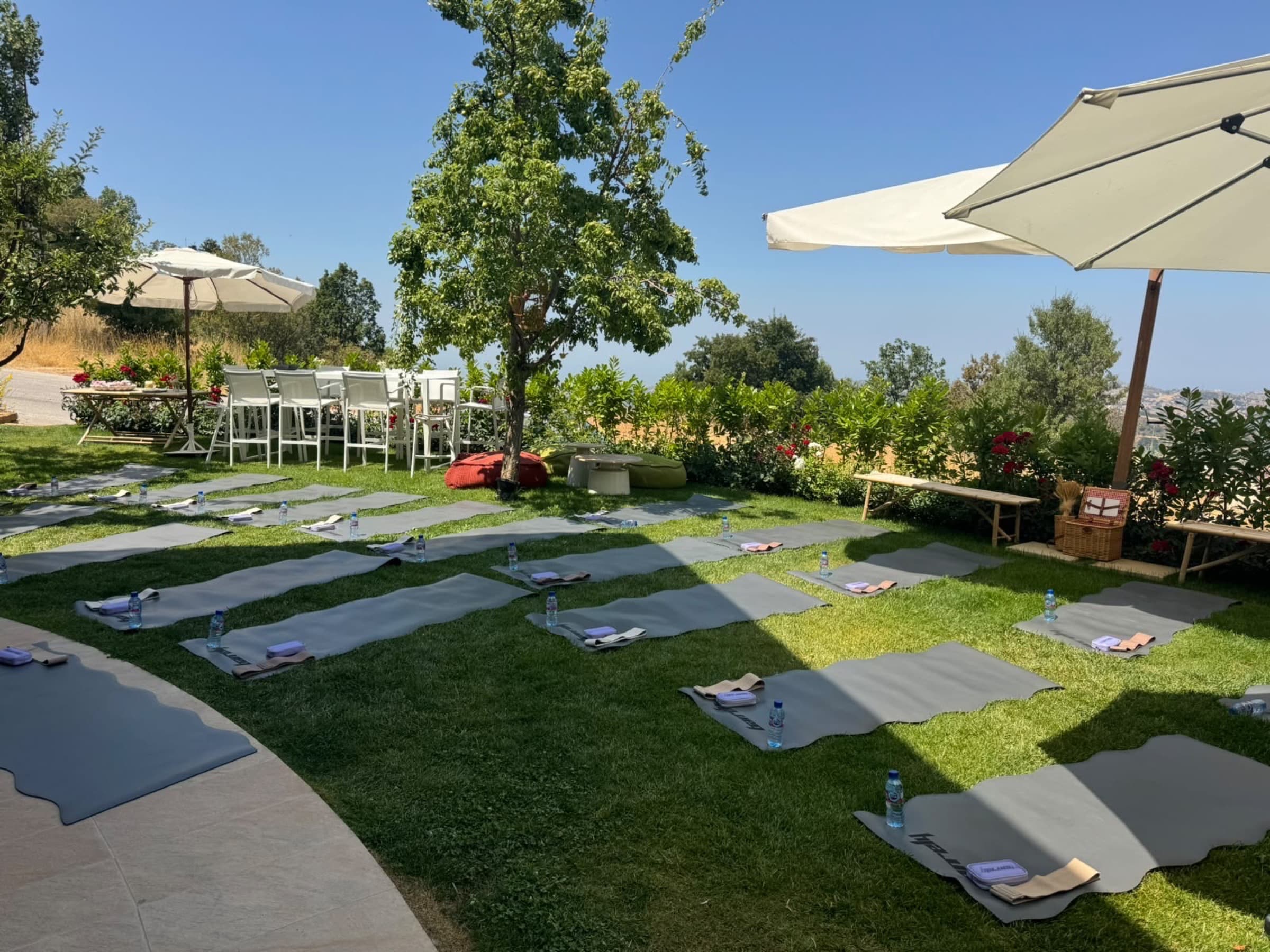 Yoga mats laid out on the grass with water bottles, mountains behind
