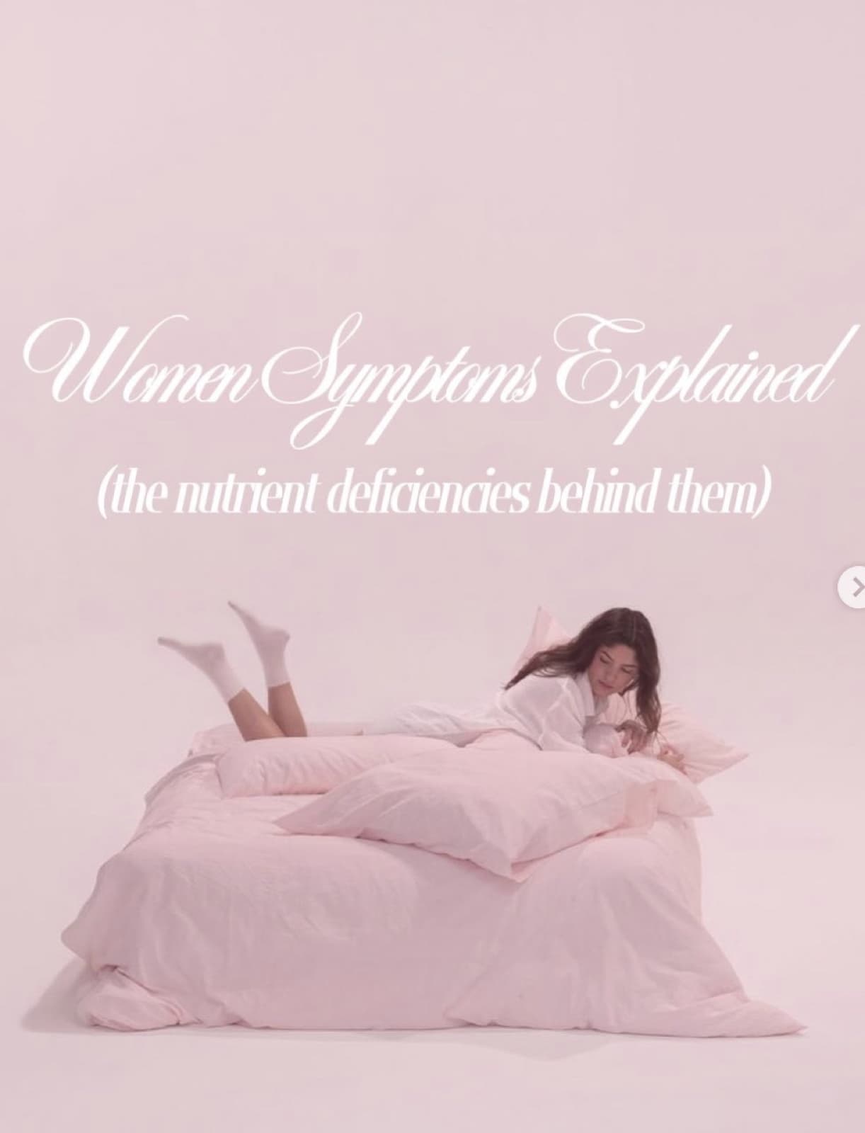 A woman lying on a pale pink bed, feet kicked up behind her