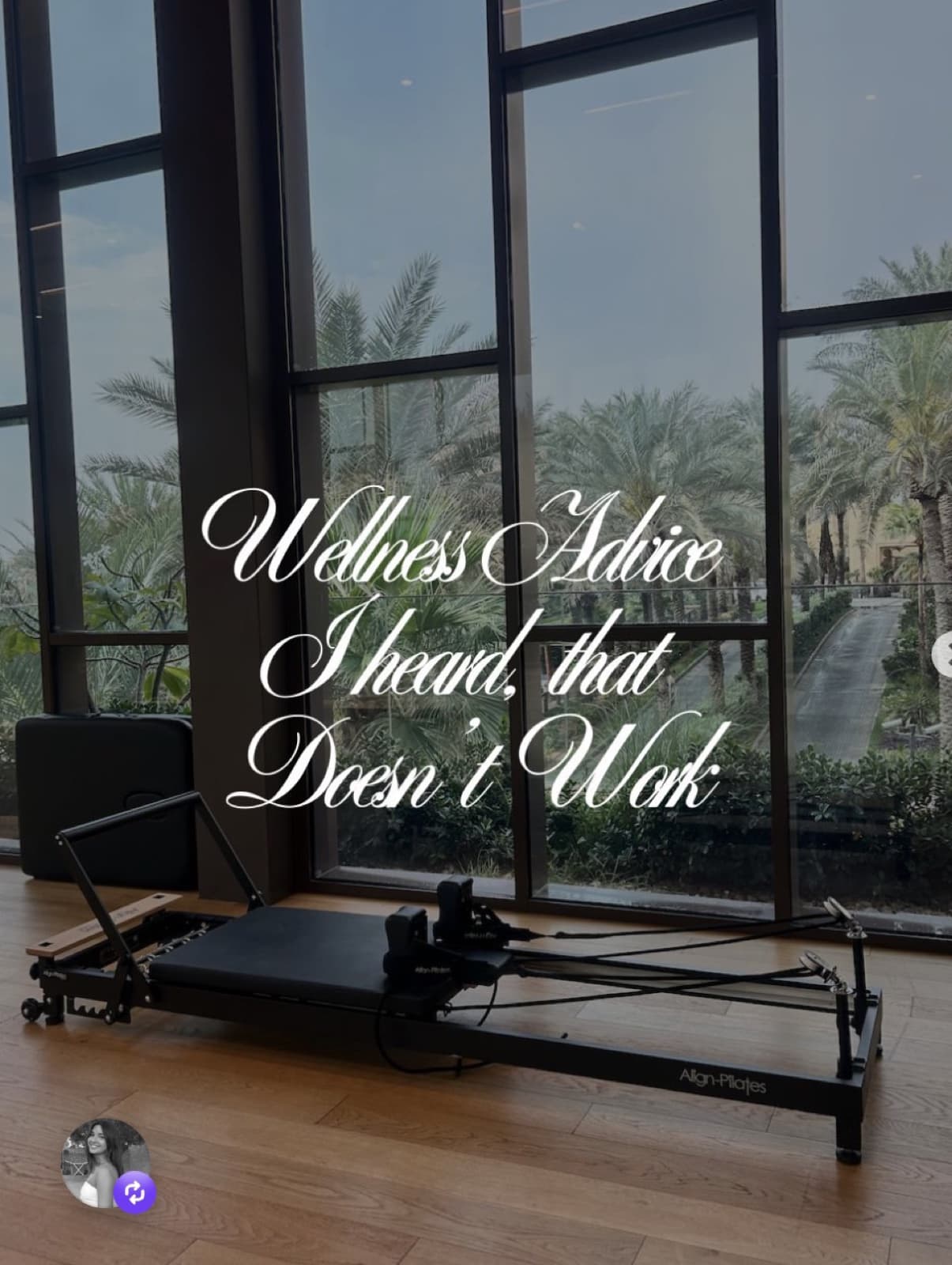 A pilates reformer in a sunlit studio, palm trees visible through floor-to-ceiling windows